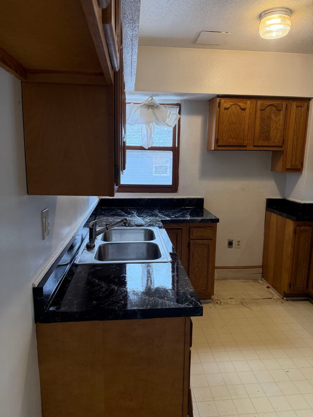 Modern kitchen with wooden cabinets, black countertops, and unfinished flooring.